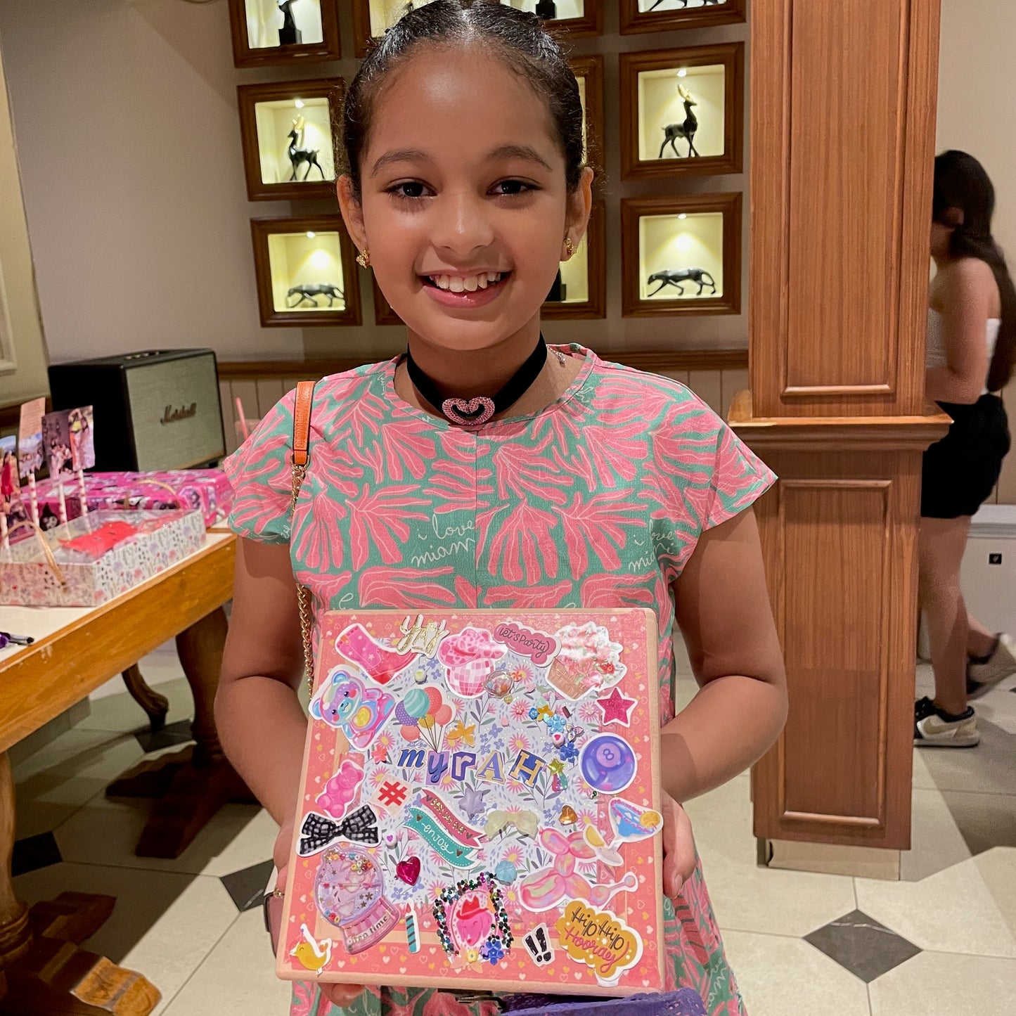 Young girl holding a decorated pink book with stickers.