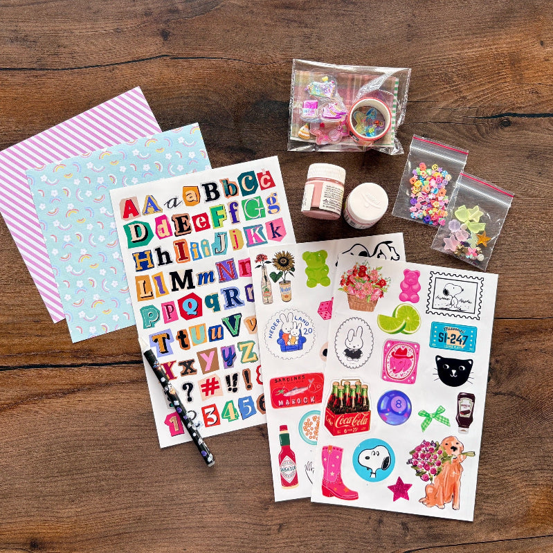Collection of stationery items including stickers, paper, and small containers on a wooden surface