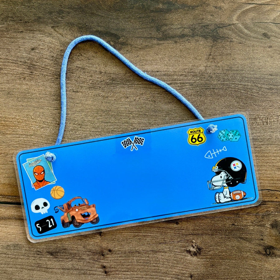 Blue name plate with various stickers on a wooden surface