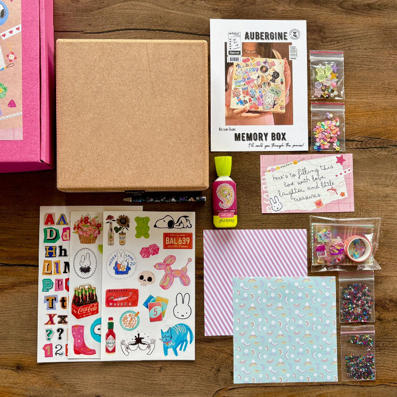 Collection of craft supplies including stickers, paper, and a memory box on a wooden surface.