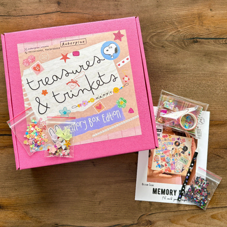 Pink box labeled 'treasures & trinkets' with decorative items on a wooden surface