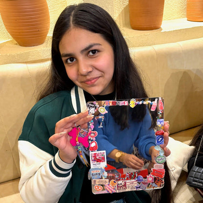 Person holding a crafted mirror with various stickers in a casual indoor setting.