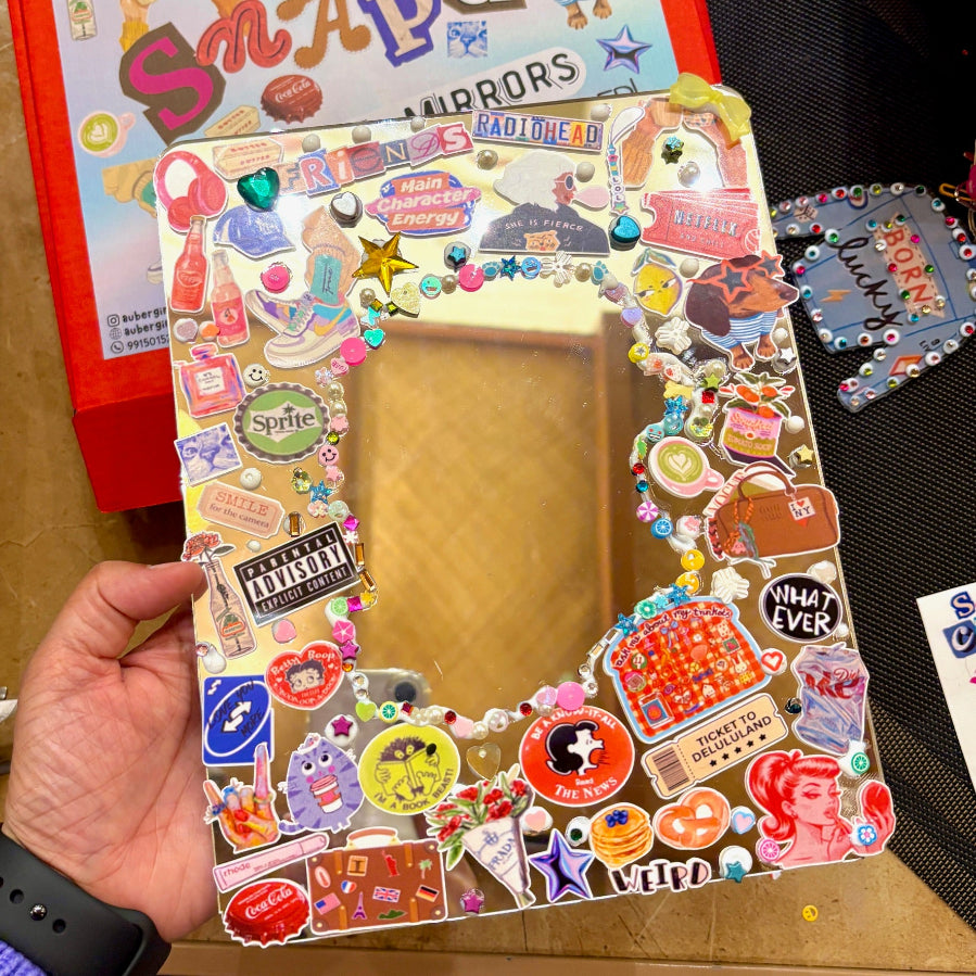 Decorative mirror with colorful stickers held by a hand